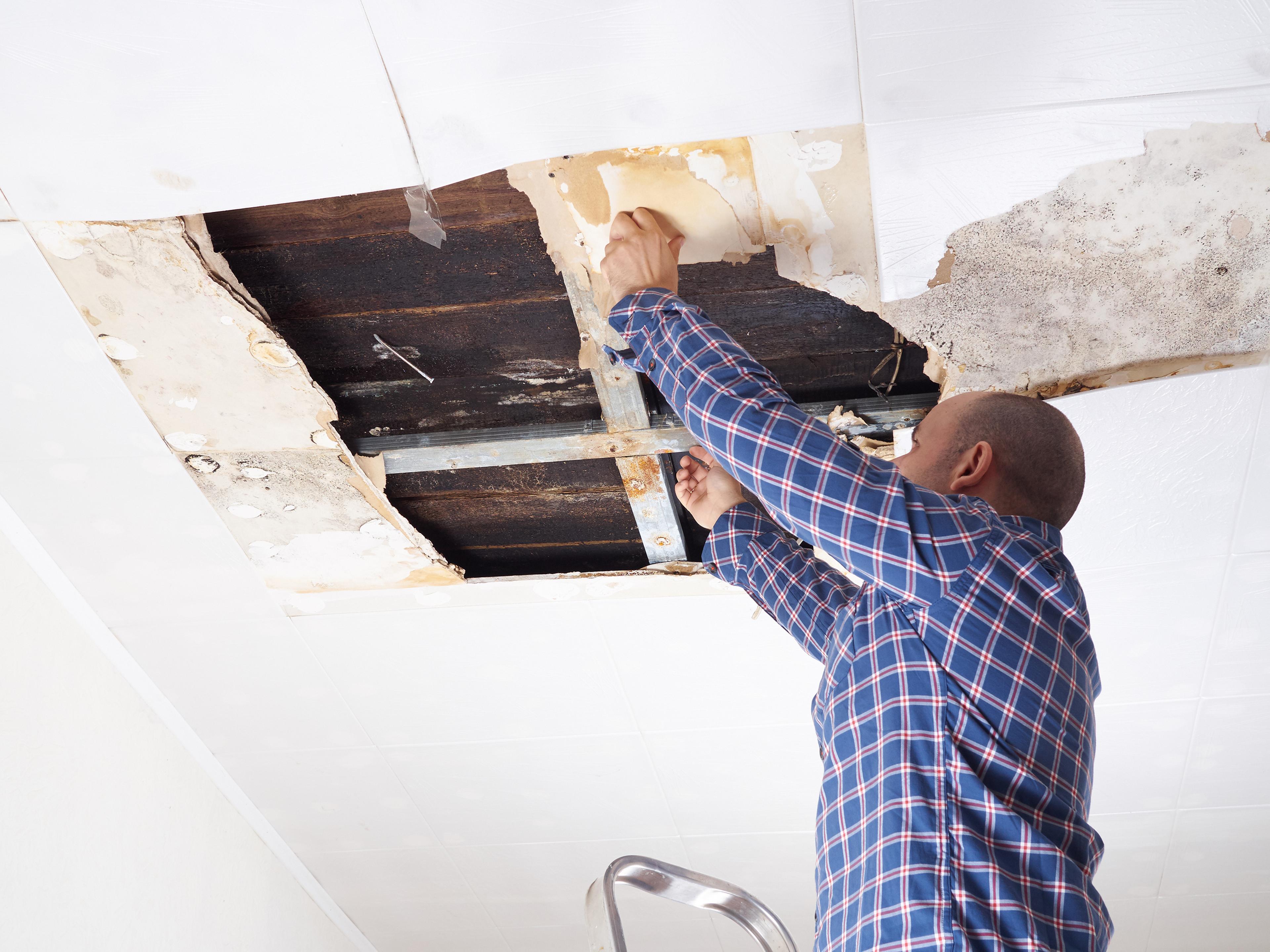 A handyman repairing drywall in a well-lit room.